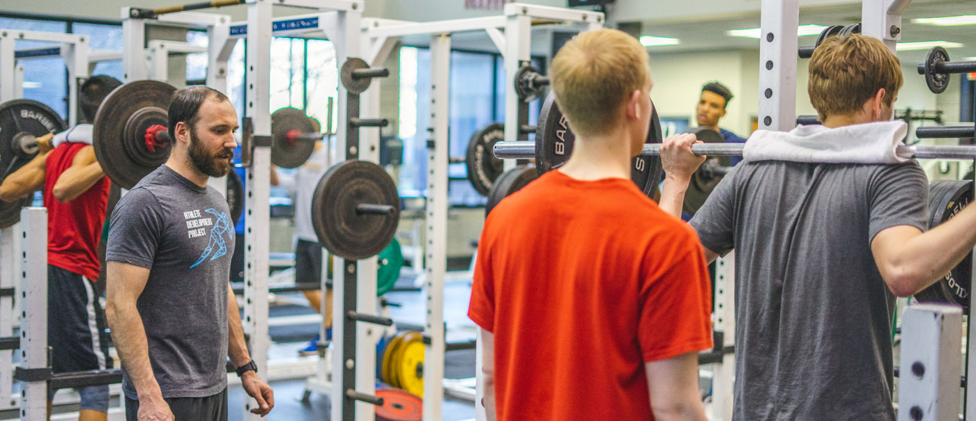 Man lifting weights with spotter